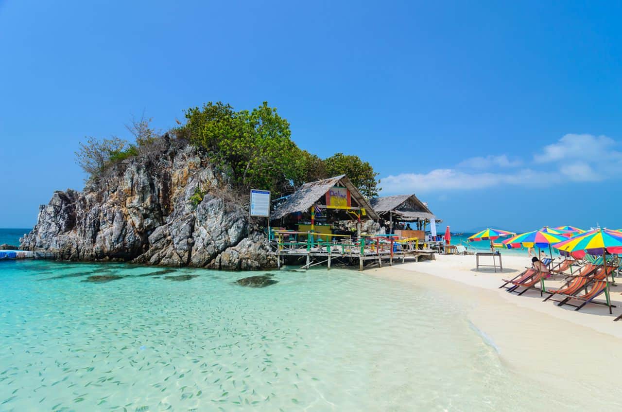 pristine-beach-in-thailand-with-colorful-umbrellas-lounge-chairs-clear-water-and-a-small-seaside-hut